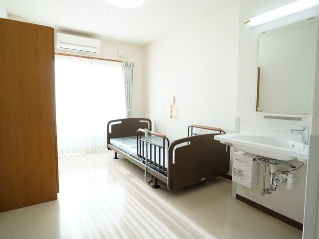 明るい洋室の居室 居室 広々とした明るい個室で、ベッドや洗面台も整っており、ゆとりを持ってお仕事ができる環境です。窓からは自然光が入り、快適な空間を提供しています。