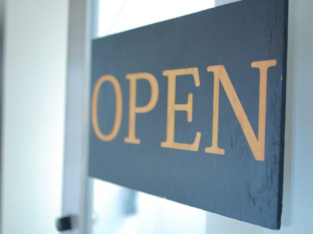 OPEN看板の入口前 エントランス   木製のOPEN看板が目を引く入口まわりです。やわらかな光が入り、落ち着いた雰囲気で迎えられます。