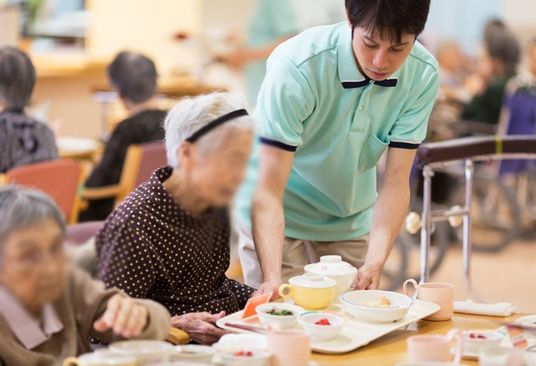 スタッフが食事補助中の食堂