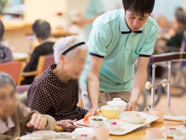 スタッフが食事補助中の食堂 食堂 広々とした食堂では、スタッフが入居者の食事を手助けしています。温かく和やかな雰囲気です。