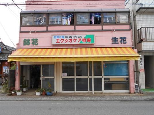ピンク外観の看板前  