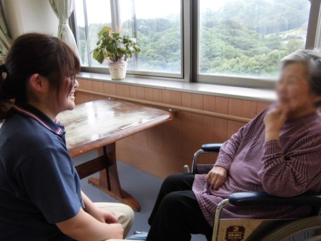 自然光あふれるラウンジ ラウンジ   明るい窓辺のラウンジで、利用者とスタッフが和やかに話しています。リラックスできる環境です。