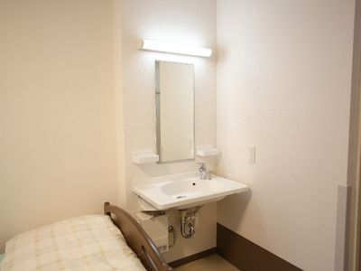 居室の洗面台とベッド