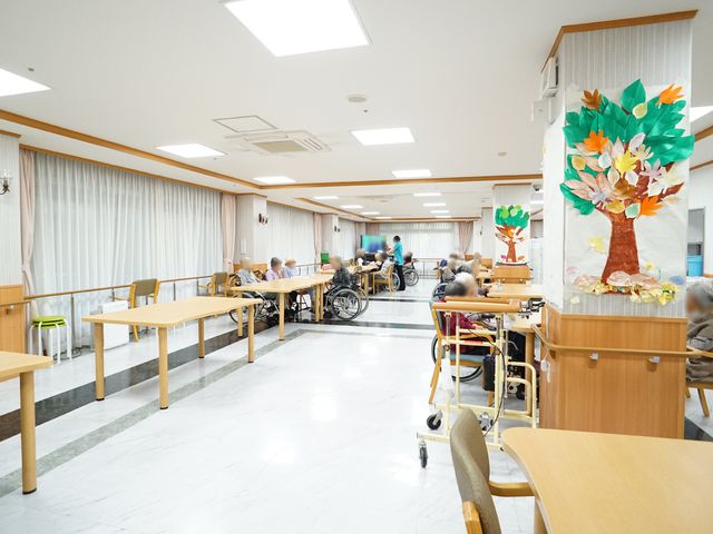 ゆったりとした食堂の風景 食堂 広々とした食堂では、車いすを利用される方々がゆったりと過ごされています。明るい壁に季節感のある装飾が施され、温もりのある空間です。