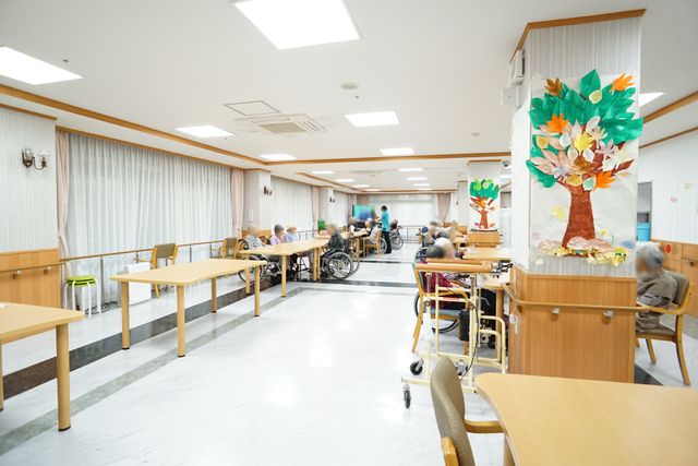 ゆったりとした食堂の風景 食堂 広々とした食堂では、車いすを利用される方々がゆったりと過ごされています。明るい壁に季節感のある装飾が施され、温もりのある空間です。