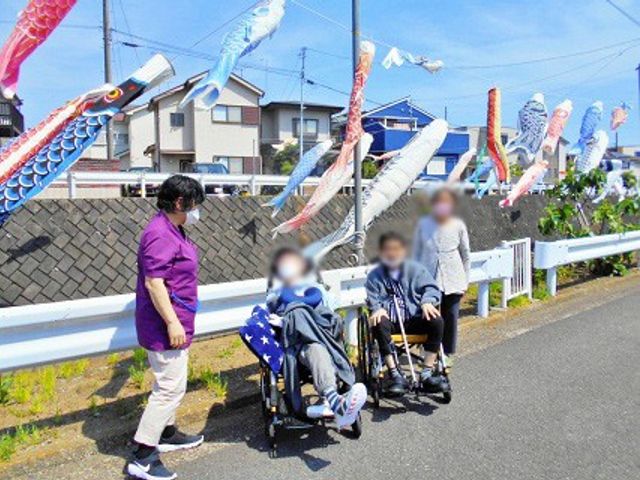 散歩中の様子 スタッフイメージ 利用者とスタッフの和やかな散歩風景です。カラフルなこいのぼりが心を和ませます。