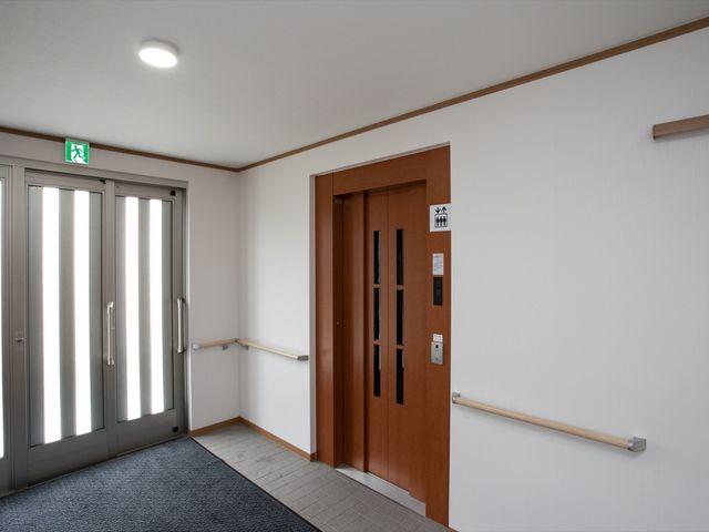 廊下と木製扉の画像 エレベーター ゆとりある廊下には、手すりが設置されており、安全に配慮された造りとなっています。ゆったりとした空間で快適な勤務を望む方に適しています。