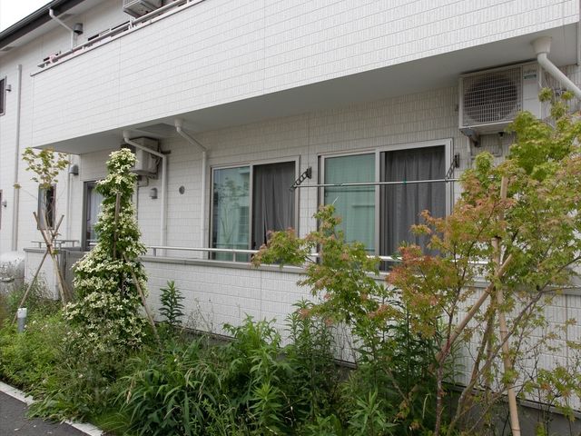 白壁の建物と緑の植物 外観 清潔感のある白い外壁と緑豊かな植栽が印象的です。ゆったりとした環境で日々を過ごせる場所です。