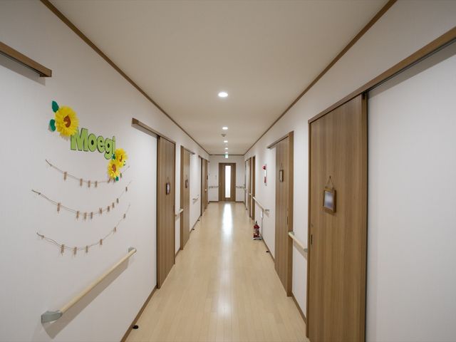 清潔感のある廊下の様子 廊下 明るく広々とした廊下は、落ち着いた色合いで統一されており、ゆったりとした移動ができる環境です。壁に飾られたデコレーションが心地よい空間を演出しています。