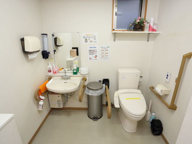 明るい清潔なトイレ空間 トイレ 広々としたバリアフリー設計のトイレで、手すりや低い鏡が利用者のサポートになっています。