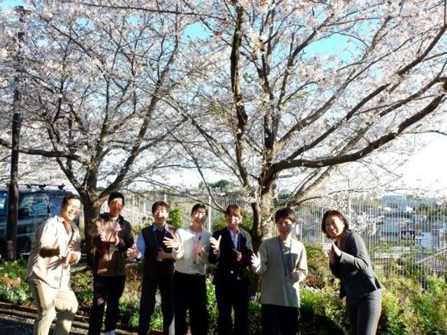 桜の下で並ぶ職員と利用者の庭  
