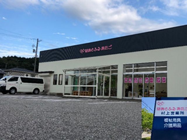白い外観の建物 外観 広々とした駐車場があり、来訪者にとってアクセスしやすい環境です。明るい空の下に佇む建物が印象的です。