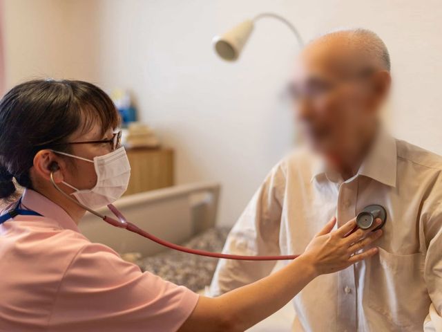 健康チェック中の居室 居室 優しい雰囲気の中で、健康チェックが行われています。職員との親密なコミュニケーションが感じられます。