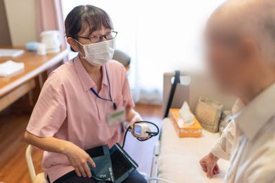 対話する看護師と高齢者の居室