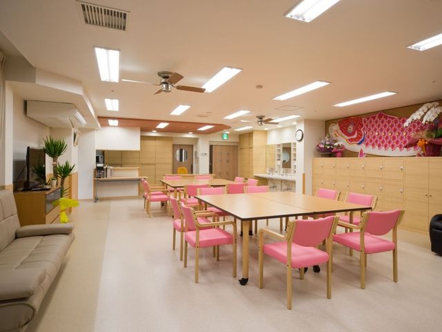 明るい食堂 食堂   明るい照明が広がる食堂で、ピンクの椅子と大きなテーブルが並んでいます。休憩や食事の場として、落ち着いて過ごしやすそうです。