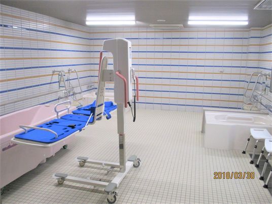 施設の写真 １人用の浴槽とリフト浴が設置され、床と壁がタイル張りの浴室