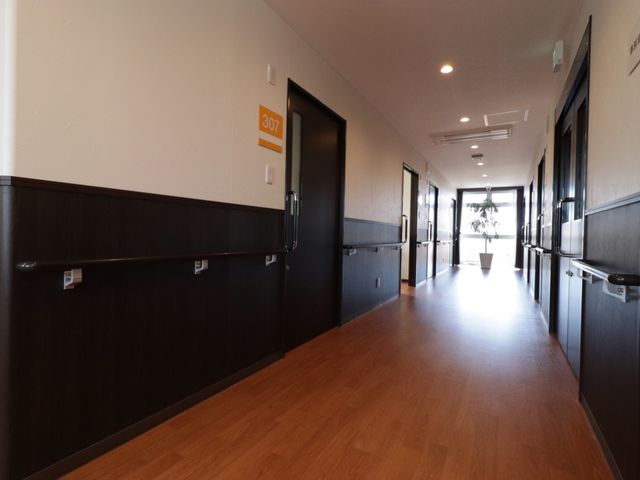 廊下の綺麗な内観 通路 床材は滑りにくく、手すりも完備しており、職場環境として安全性に配慮されています。明るく清潔感のある通路が心地よい空間を演出しています。
