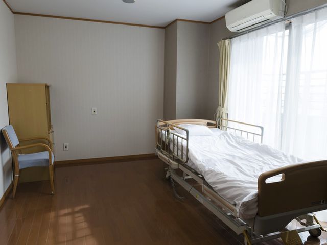 静かな居室 居室 日当たりの良い居室は、快適で落ち着いた空間になっています。ベッドの横には椅子があります。