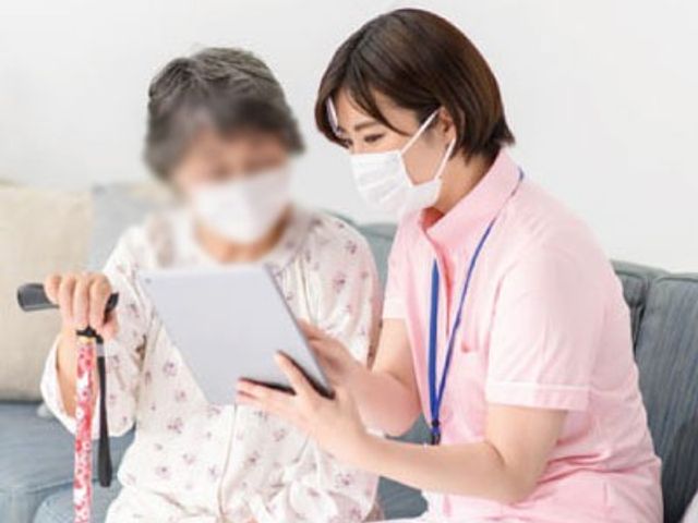 スタッフと談笑中の女性 ラウンジ 広々としたラウンジで、スタッフが利用者と楽しそうにお話しをされています。安心してお仕事ができる環境です。