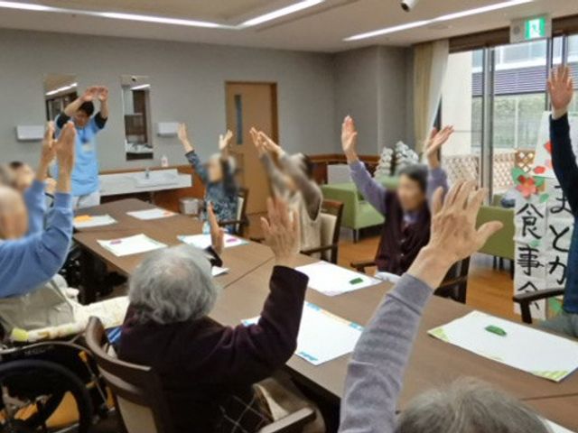 活動の様子の室内 多目的室 入居者の皆様が集まり、体操を楽しんでおられます。和やかな雰囲気が漂う場となっています。