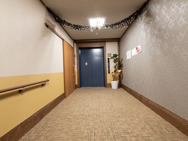 廊下の角とエレベーター 廊下 手すりがついた温かみのある廊下です。通路は広く、ゆったりと歩ける設計になっております。