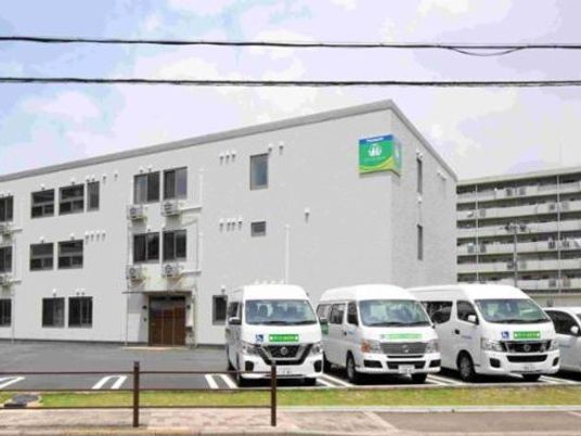 施設外観と送迎車両の並ぶ外観  
