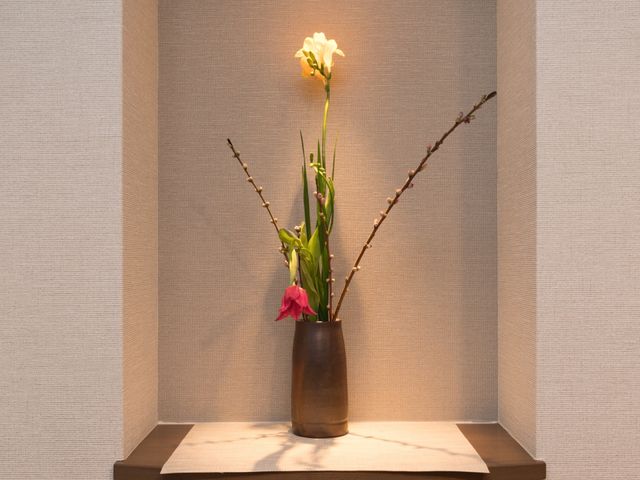 エントランスの花瓶と花 生け花 落ち着いた色合いの空間に飾られた生花が、お出迎え時の心地よさを演出しています。日々の生活に彩りを加える細やかな配慮が感じられる環境です。