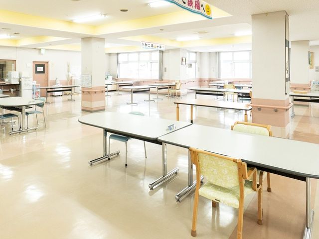 明るい食堂の机 食堂   広い食堂に机がゆったり並び、窓から自然光が入る明るい空間です。車椅子でも動きやすそうで、働く場としても見通しがよさそうです。