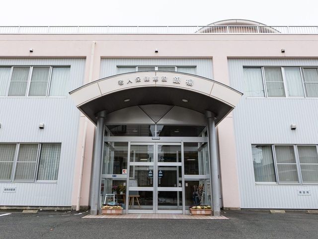 施設の正面入口 外観   大きなひさしのある正面入口で、ガラス扉から館内の様子が見えます。明るく落ち着いた印象で、来訪者を迎えやすそうです。