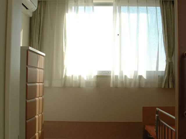 日差し溢れる居室風景 居室 窓から降り注ぐ柔らかい日差しが心地よい、ゆったりとした空間の部屋です。清潔感のある壁と床が、心穏やかな時間を演出しています。