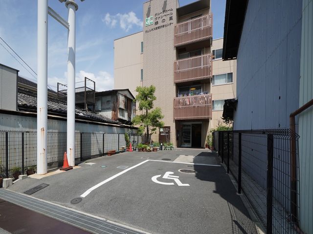 駐車場と建物の外観 外観 広々とした駐車スペースが整備されたエントランス周辺です。バリアフリー設計で、どなたでも快適にお過ごしいただける環境が整っています。