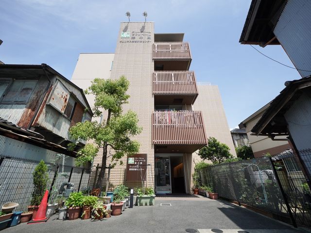 緑ある施設のエントランス 外観 緑に囲まれた入り口は開放的で、心地よい第一歩を踏み出せるように設計されています。明るく迎える空間が、訪れる皆様に安心感を提供します。