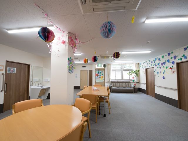 装飾のある共有スペース 談話室 色とりどりの飾りが天井に吊るされた、居心地の良い共有スペースです。ソファやテーブルがあり、ゆったりと過ごすことができます。