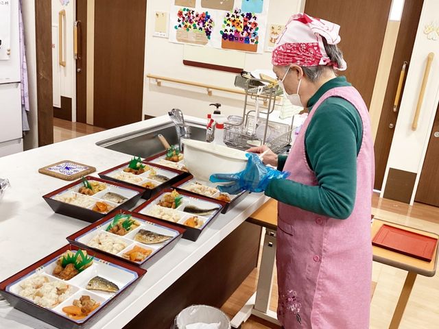 調理作業をするスタッフの様子 キッチン スタッフが温かい雰囲気の中で食事を準備しています。安心して働ける環境です。