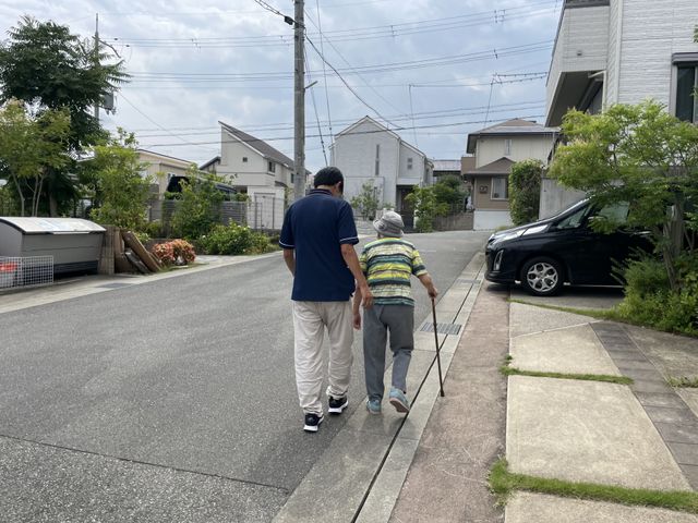 人々が歩く道 外観 スタッフが高齢者と一緒に地域の道を歩いています。温かい交流が感じられます。