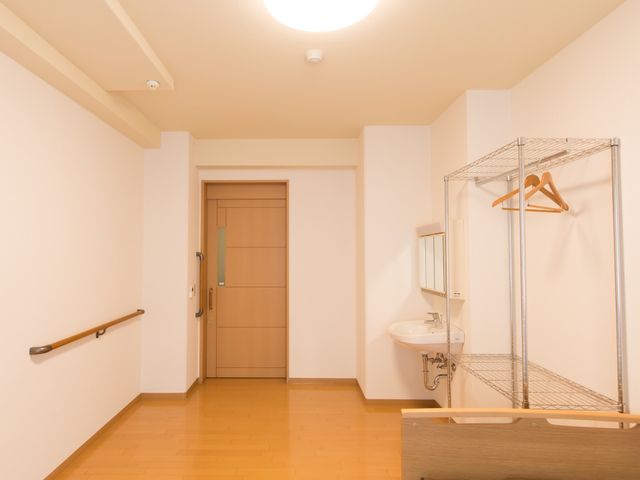 居室の手すりと洗面台 居室 壁には手すりが取り付けられた清潔感のある居室です。ご入居者様は日々の生活を安全かつ快適にお過ごしいただけます。