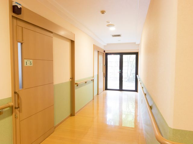 明るい廊下と部屋の扉 廊下 ゆとりのある廊下が広がっており、清潔感のある快適な環境で働けます。明るい窓付きの扉は、開放感を演出しています。