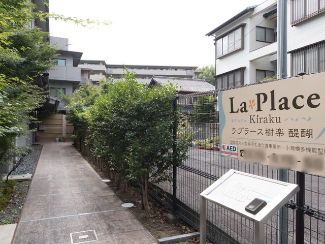看板とエントランスの景色 出入り口 清潔感があり、安心して新しい生活を始められるエントランスです。利用者の方々が穏やかな時間を過ごせる環境が整っています。