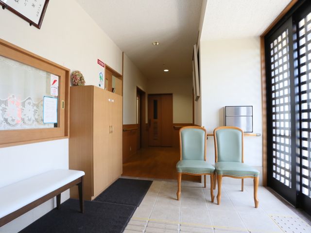 待合室の椅子と掲示板 玄関 落ち着いた色合いのエントランスには、待合席が整い、掲示物が訪れる人々への情報を提供しています。