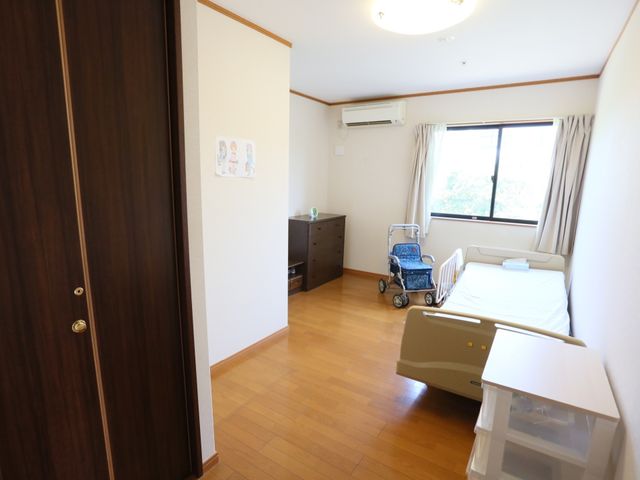 広々とした明るい居室 居室 天井が高く、自然光が差し込む居室です。ベッド脇には移動に便利な歩行器も配備されており、安心してお過ごしいただけます。