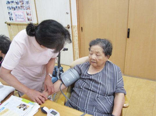 血圧を測るスタッフと利用者