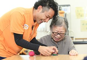 笑顔で手作業を支援するスタッフ