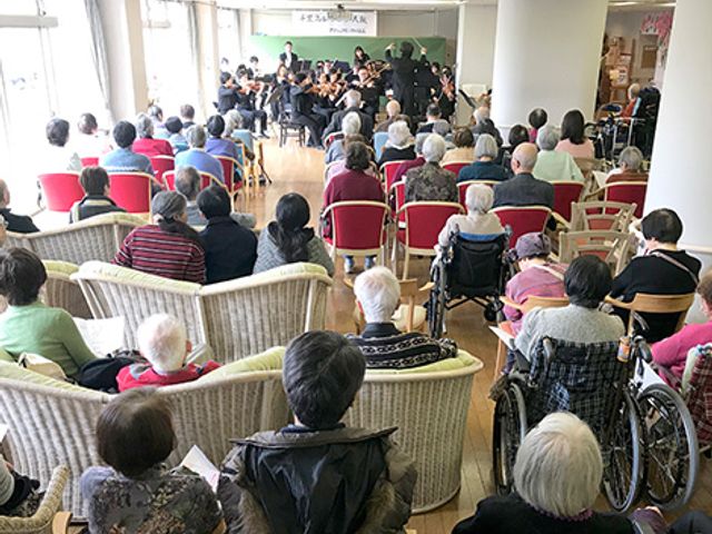 音楽イベントの室内 多目的室 リビングには音楽イベントが開催されており、多くの方がリラックスした雰囲気の中で楽しんでいます。自然光が差し込み、開放感があります。
