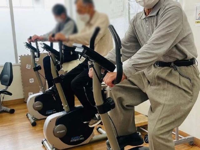トレーニングに励む様子の機能訓練室 機能訓練室 自然光が差し込む機能訓練室では、自転車型のトレーニング機器を使用して体を動かせます。