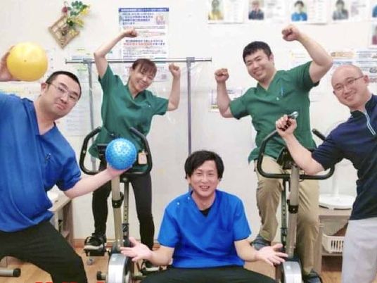 笑顔のスタッフが集合する機能訓練室