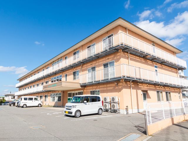青空に映える建物外観 外観 広々とした駐車スペースを備えた建物です。晴天の日に外観が映えます。