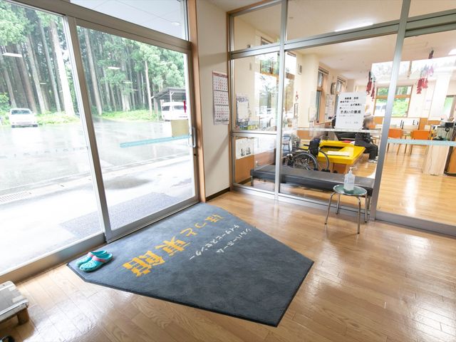 エントランスの横顔 玄関 広々と開放感のある入口から、自然光溢れる休憩スペースが望めます。ガラス越しに見える緑豊かな景色が、訪れる方々の心を和ませてくれることでしょう。
