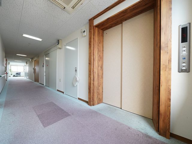 ゆったりした廊下の一角 エレベーター ゆったりとした通路は、明るく開放的な雰囲気で、来訪者をやさしく迎え入れています。実際に働く空間の一部を垣間見れば、快適な労働環境が想像できます。