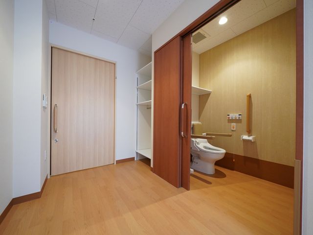 洗練されたトイレの一室 居室 ゆとりあるスペースの清潔なトイレです。手すりが設置されており、すべての方が安心してご利用いただけます。