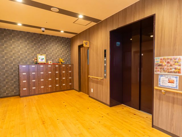 モダンな廊下とエレベーター エレベーター 手すりが設置された落ち着いた色調の廊下です。ゆったりとした設計で、安心して歩行できる環境が整っています。